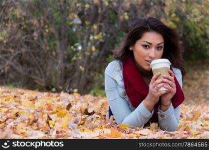 Hispanic woman enjoying a coffee outdoors during autumn