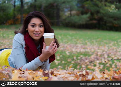 Hispanic woman enjoying a coffee outdoors during fall