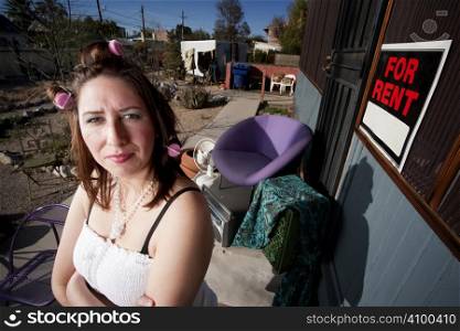 Hispanic woman in front of house with messy yard