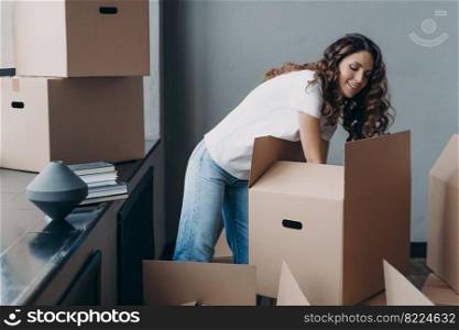 Hispanic woman unpack carton boxes with delivered things during relocation. Satisfied female tenant homeowner sorting belongings on moving day at new home. Real estate rental, mortgage.. Hispanic woman unpack boxes with delivered things during relocation at new home. Moving, delivery