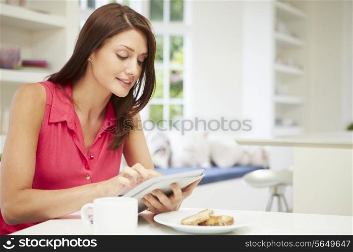 Hispanic Woman Using Digital Tablet In Kitchen At Home
