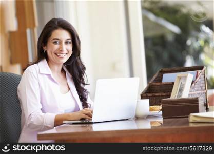 Hispanic Woman Using Laptop On Desk At Home