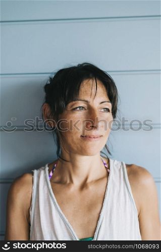 Hispanic woman with summer dress and ponytail while leaning on wood wall