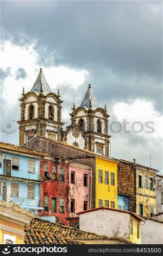 Historic baroque church tower behind the facades of old colonial style houses in Pelourinho in the city of Salvador, Bahia. Tower of historic baroque church behind old colonial houses in Pelourinho