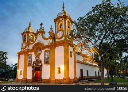 Historic church in the city of Tiradentes in Minas Gerais with its facade lit up at dusk. Historic church facade in the city of Tiradentes