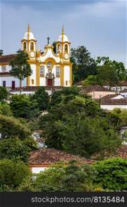 Historic colonial-style church surrounded by houses and greenery in the city of Tiradentes in Minas Gerais, Brazil. Historic colonial-style church surrounded by houses in the city of Tiradentes 