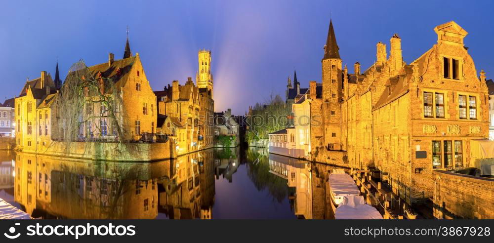 Historic medieval buildings along a canal in Bruges, Belgium at dusk.