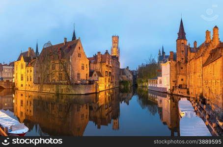 Historic medieval buildings along a canal in Bruges, Belgium at dusk.