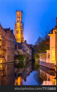 Historic medieval buildings along a canal in Bruges, Belgium at dusk.