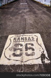 Historic Route 66 marker in Kansas on asphalt.