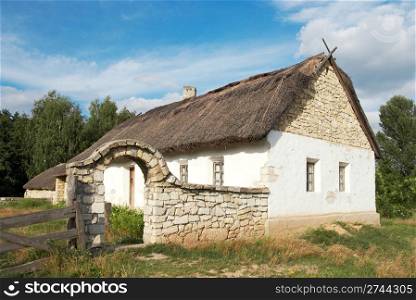 historical country farmstead with stone fence and arc (preceding century, museum of Ukrainian folk architecture in Pirogovo village (near Kiev))