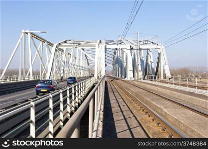 Historical Dutch bridge with separated railway and car lanes crossing the river IJssel at the city Westervoort, the Netherlands.