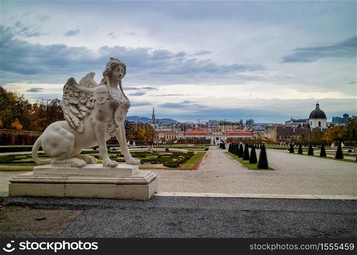 Historical landscape with marble sculpture of Woman Sphinx on a parapet of Schloss Belvedere Palace in Vienna, Austria on a background of grey cloudy sky on autumn day.. Marble statue of Woman Sphinx on a parapet of Belvedere Palace in Vienna.