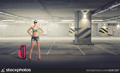 Hitch hiker woman on parking. Beautiful woman in swimsuit standing in underground parking