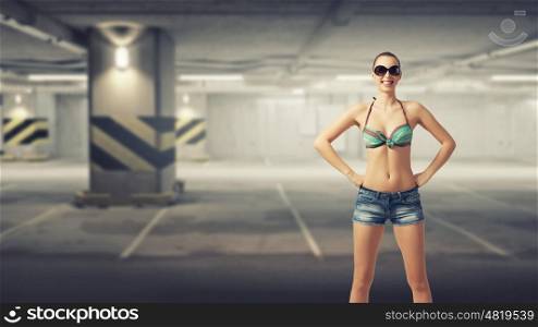 Hitch hiker woman on parking. Beautiful woman in swimsuit standing in underground parking