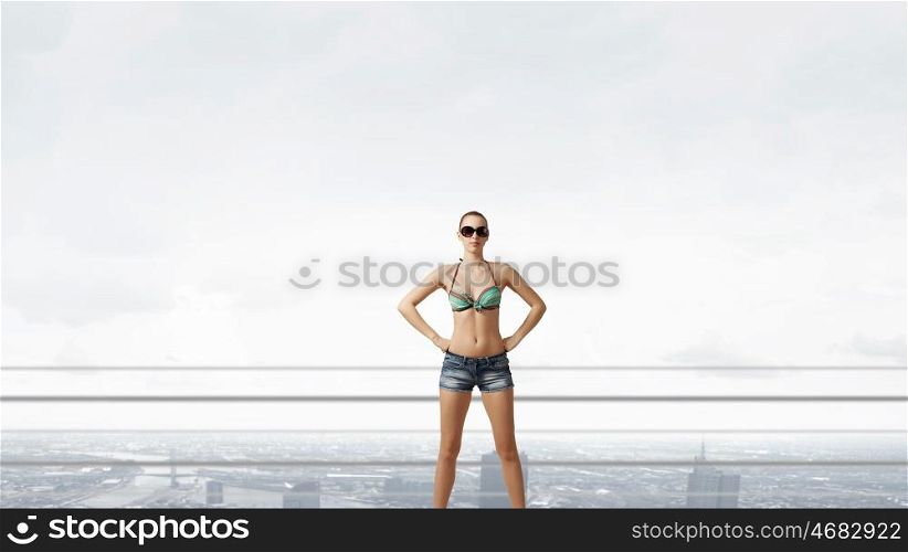 Hitch hiker woman on roof. Young attractive girl in bikini and shorts on building roof