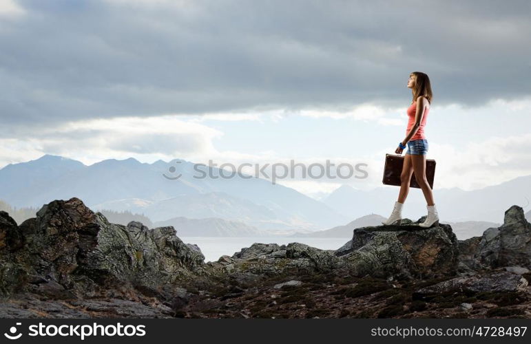 Hitch hiking traveling. Young pretty woman walking with her vintage baggage in hand