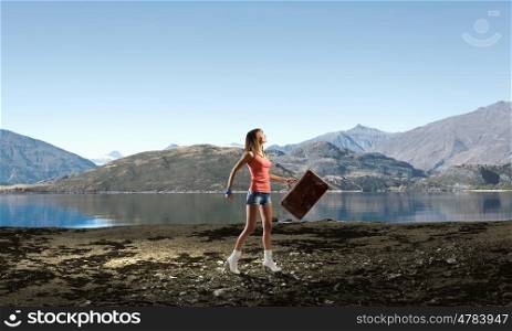 Hitch hiking traveling. Young pretty woman walking with her vintage baggage in hand