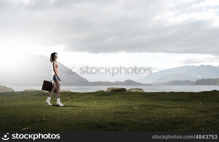 Hitch hiking traveling. Young pretty woman walking with her vintage baggage in hand