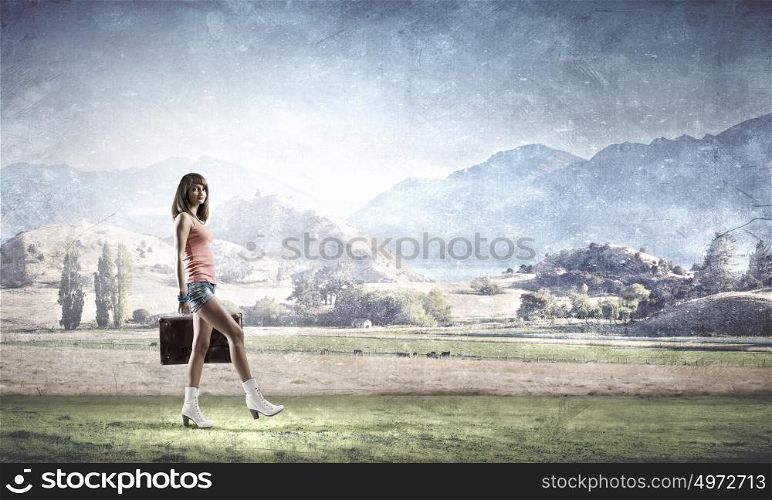 Hitch hiking traveling. Young pretty woman walking with her vintage baggage in hand