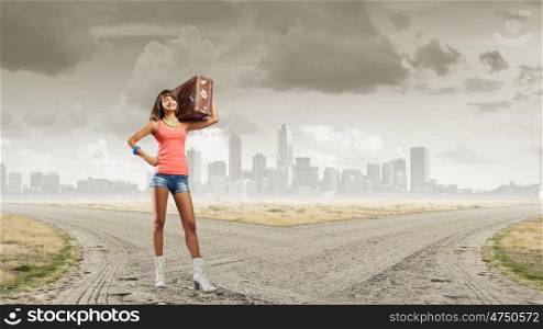 Hitch hiking traveling. Young retro woman with her vintage baggage on shoulder