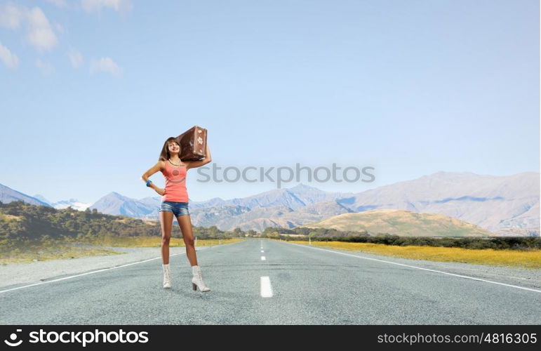 Hitch hiking traveling. Young retro woman with her vintage baggage on shoulder