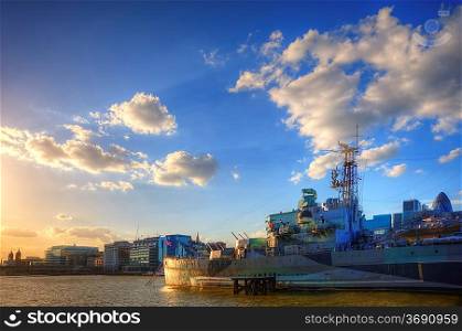 HMS Belfast docked on River Thames in London bathed in late afternoon sunlight