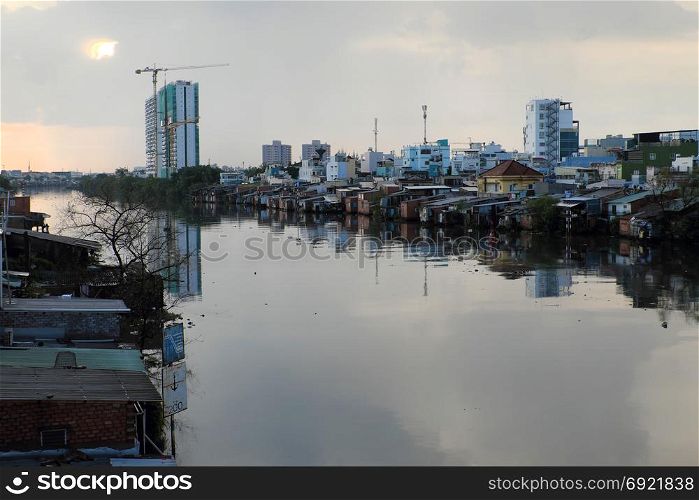 HO CHI MINH CITY, VIET NAM- NOV 21, 2017: Riverside residential at evening after rain, group of temporary house that downgrade from metal sheet or red brick, poor houses danger near river
