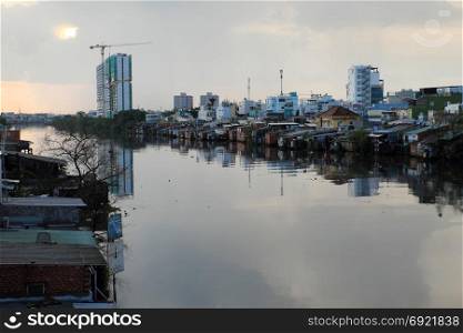 HO CHI MINH CITY, VIET NAM- NOV 21, 2017: Riverside residential at evening after rain, group of temporary house that downgrade from metal sheet or red brick, poor houses danger near river