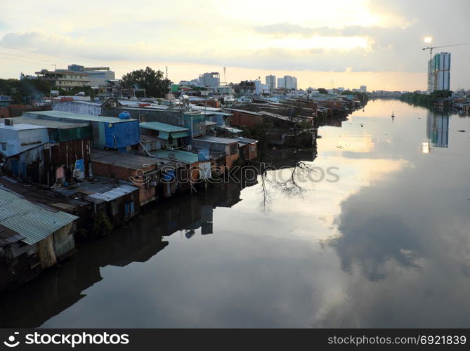 HO CHI MINH CITY, VIET NAM- NOV 21, 2017: Riverside residential at evening after rain, group of temporary house that downgrade from metal sheet or red brick, poor houses danger near river