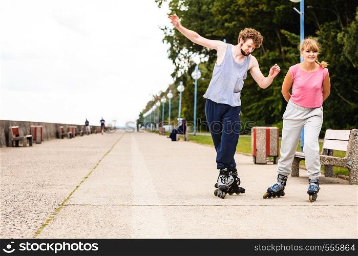 Hobby and spending free time in summer. Sport and exercising. Healthy body and wellbeing. Couple have fun together rollerblading outdoors.. Young people casually rollblading together.