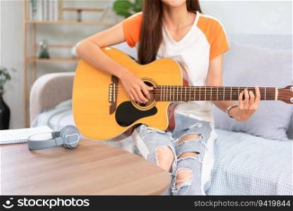 Hobby concept, Young asian woman sit on couch to playing music with acoustic guitar in living room.