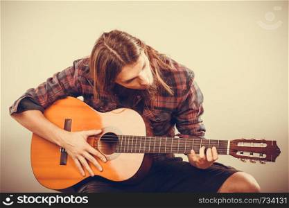 Hobby passion concept. Guitarist is playing the guitar. Long haired performer and his instrument.. Guitarist is playing the guitar.