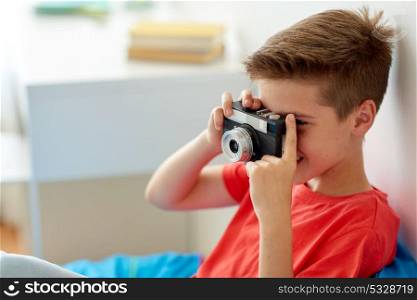 hobby, technology and people concept - happy boy with film camera photographing at home. happy boy with film camera photographing at home