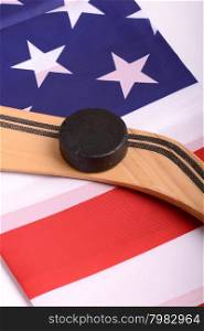 Hockey equipment including a stick and puck on an American flag to infer a patriotic American sport.