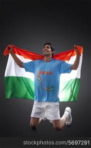 Hockey player looking up as he holds Indian flag with pride against black background