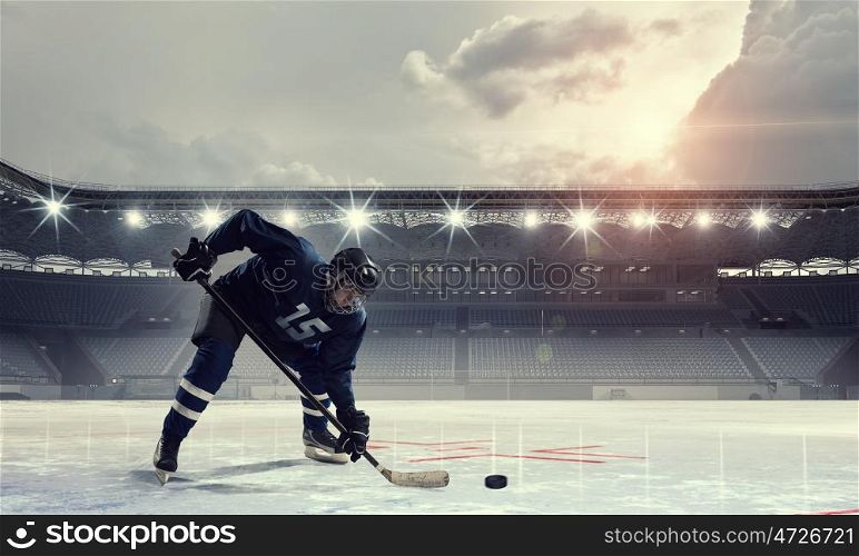 Hockey player on ice mixed media. Hockey player in blue uniform on ice rink in spotlight