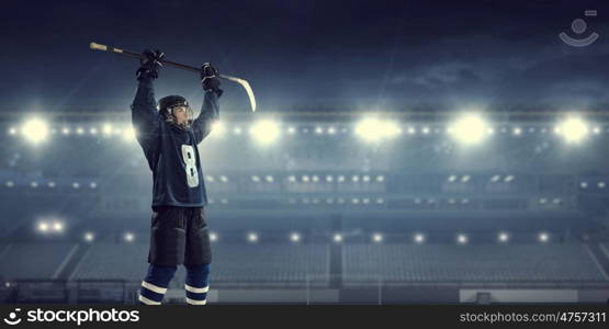 Hockey player on ice mixed media. Hockey player in blue uniform on ice rink in spotlight