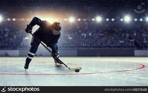 Hockey player on ice mixed media. Hockey player in blue uniform on ice rink in spotlight