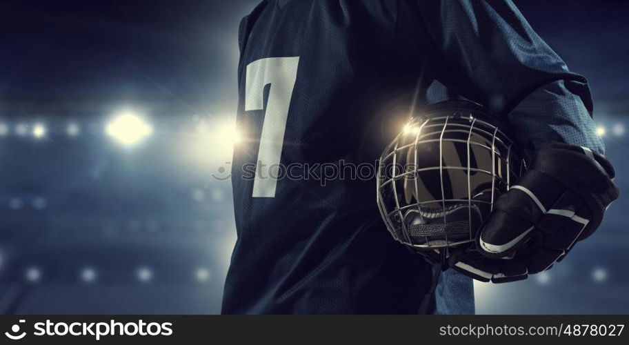 Hockey player on ice mixed media. Hockey player in blue uniform on ice rink in spotlight