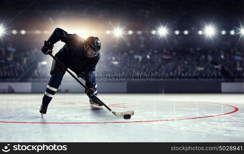 Hockey player on ice mixed media. Hockey player in blue uniform on ice rink in spotlight