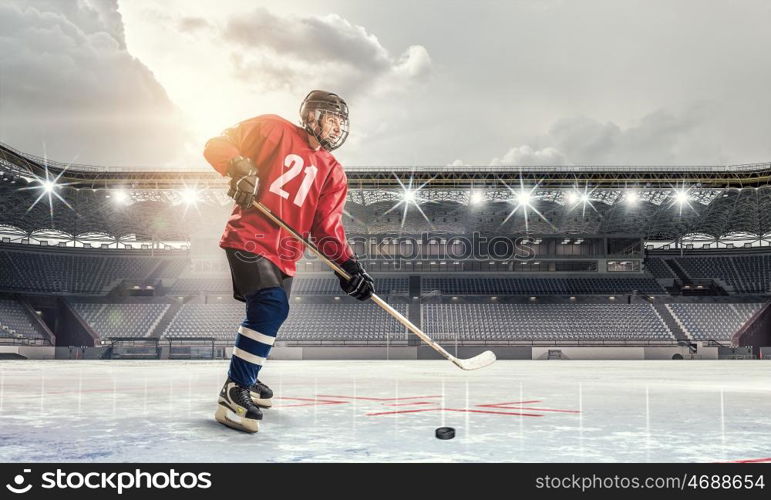 Hockey player on ice mixed media. Hockey player in red uniform on ice rink in spotlight