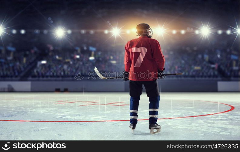 Hockey player on ice mixed media. Hockey player in red uniform on ice rink in spotlight