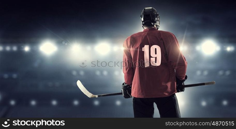 Hockey player on ice mixed media. Hockey player in red uniform on ice rink in spotlight
