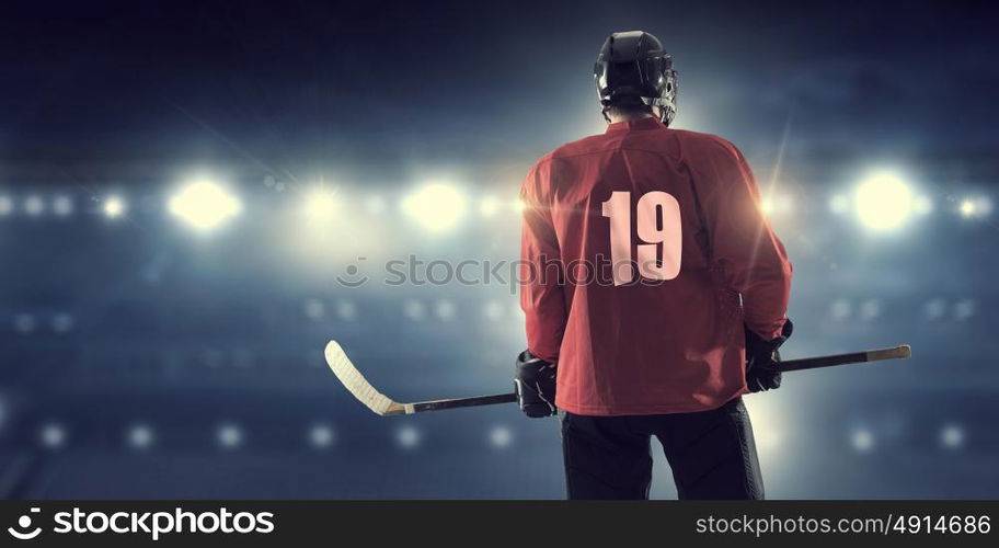 Hockey player on ice mixed media. Hockey player in red uniform on ice rink in spotlight