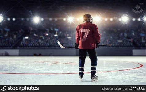 Hockey player on ice mixed media. Hockey player in red uniform on ice rink in spotlight