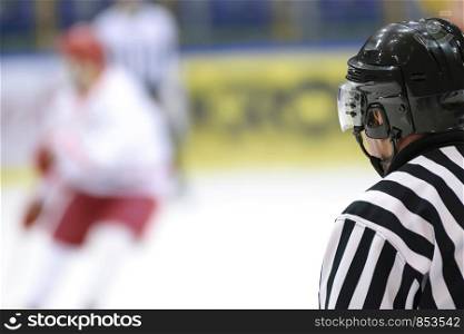 Hockey sport background - rear view of the referee against the blurry hockey game.