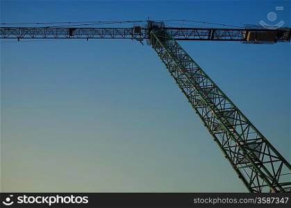 Hoisting crane against evening sky
