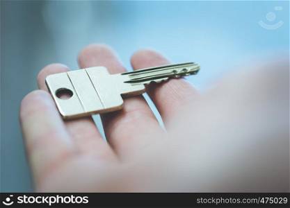 Holding a house key in the hand: New home and property.