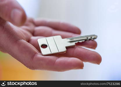 Holding a house key in the hand: New home and property.